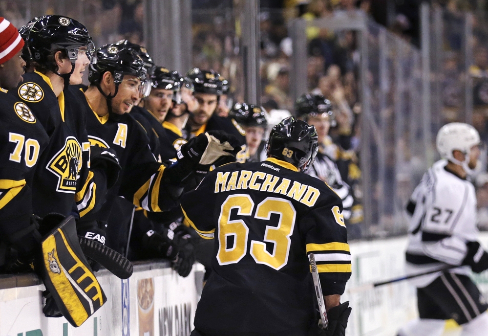Brad Marchand of the Boston Bruins is congratulated by teammates Saturday night after scoring in the second period of a 3-1 victory against the Los Angeles Kings in Boston. Marchand later scored into an empty net.