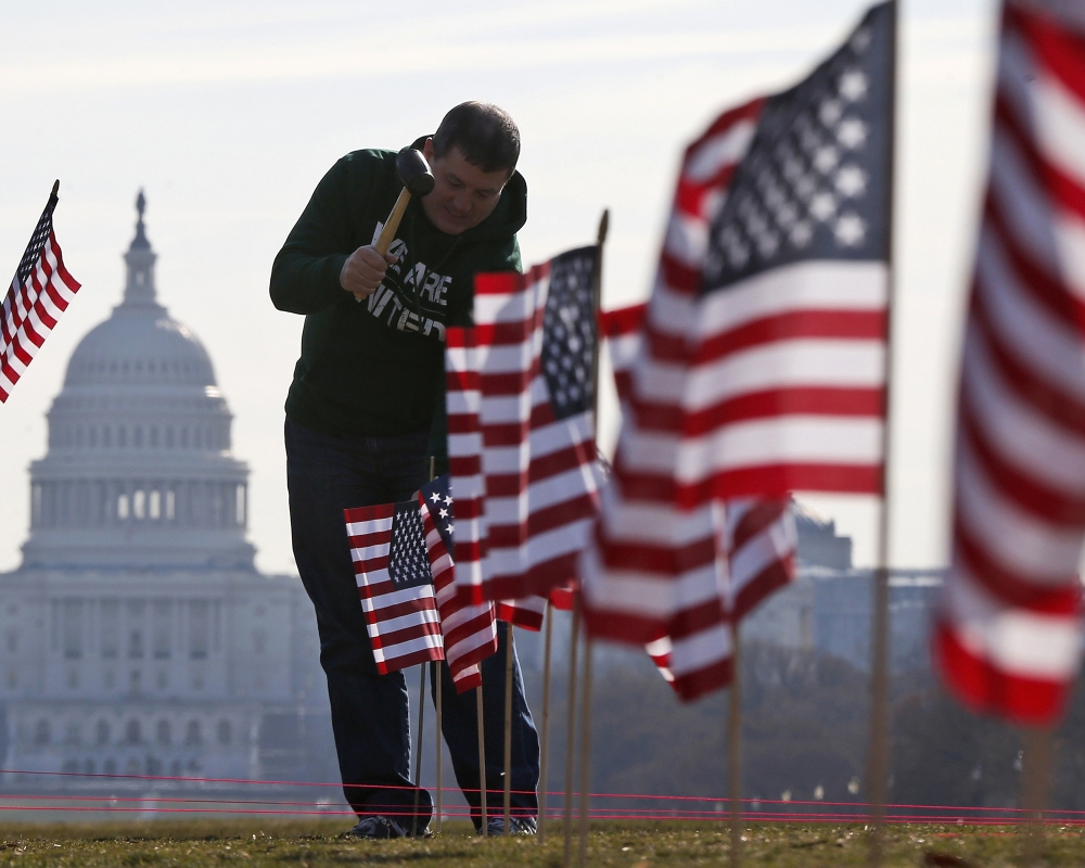 With the Capitol in the background, flags representing veterans and service members who died by suicide in 2014 are placed on the National Mall in Washington.