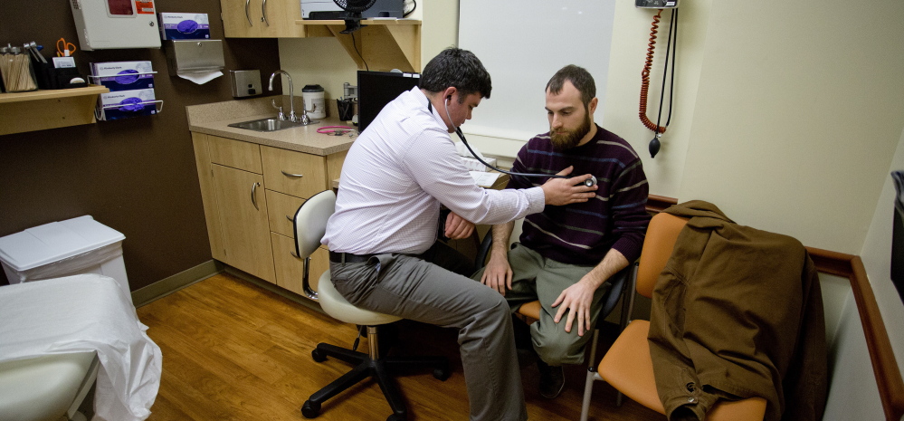 Dr. Brad Huot, a primary care physician at Martin’s Point Health Care, checks the heart rate of patient Tyson O’Keefe of Portland. A hybrid form of Medicaid expansion would help more Mainers access care.