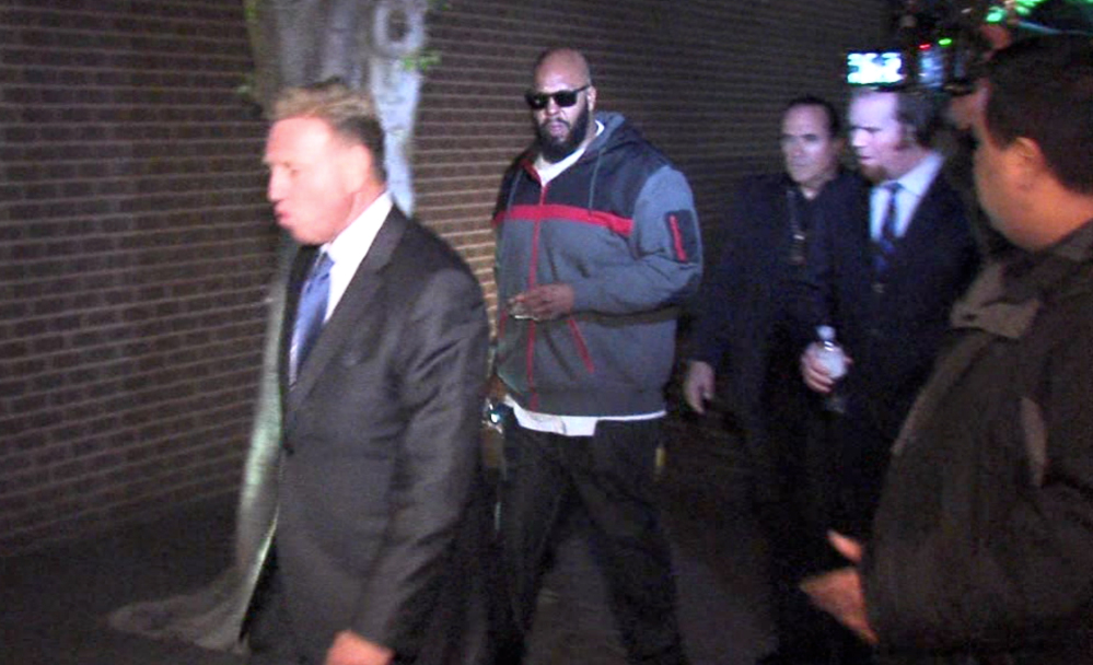 Death Row Records founder Marion “Suge” Knight, right, walks into the Los Angeles County Sheriff’s Department early Friday morning in connection with a hit-and-run that killed one man and another injured. Knight was charged Monday with murder and attempted murder.