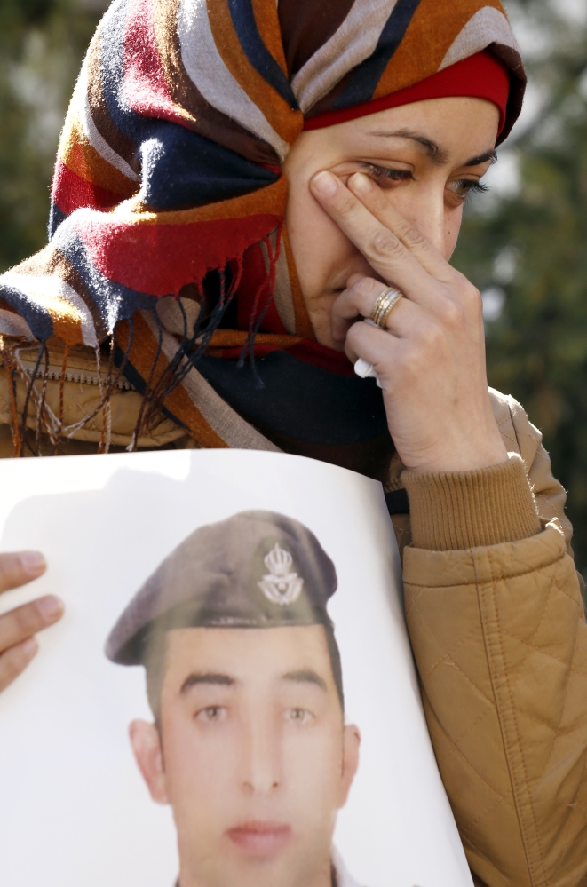 Anwar al-Tarawneh, the wife of Jordanian pilot Lt. Muath al-Kaseasbeh, who was killed by Islamic State group militants, holds a poster of him as she weeps during a protest in Amman, Jordan, on Tuesday.