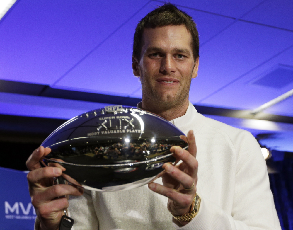 New England Patriots quarterback Tom Brady holds up his Pete Rozelle Trophy during a news conference after the NFL Super Bowl XLIX football game Monday in Phoenix, Ariz.