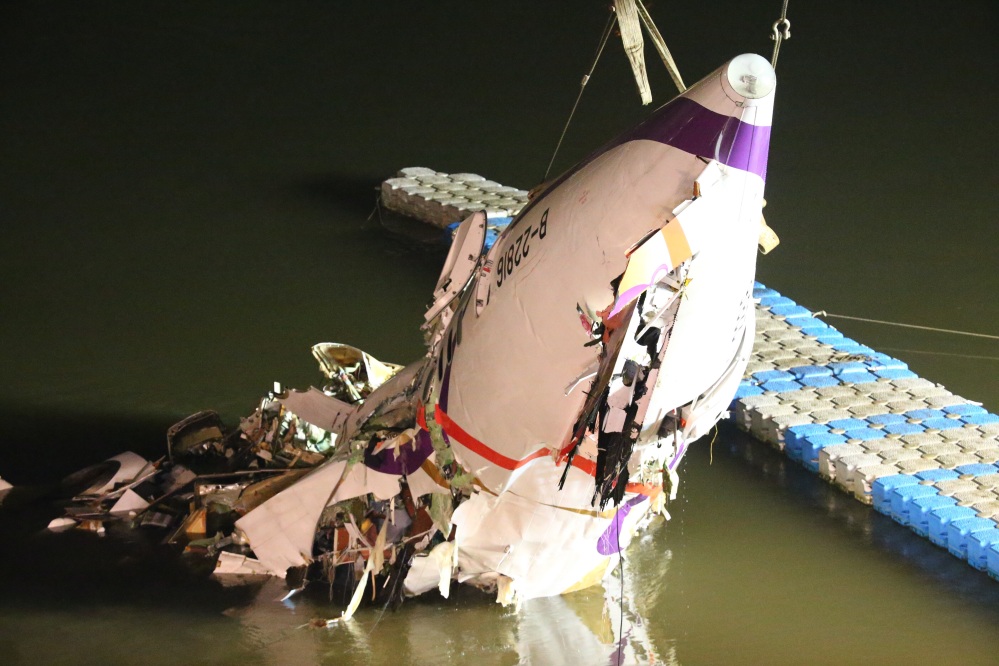 The mangled fuselage of the TransAsia Airways plane is dragged to a riverbank Wednesday after the crash in Taipei, Taiwan. The commercial flight with 58 people aboard clipped a bridge shortly after takeoff and crashed into a river Wednesday morning.
