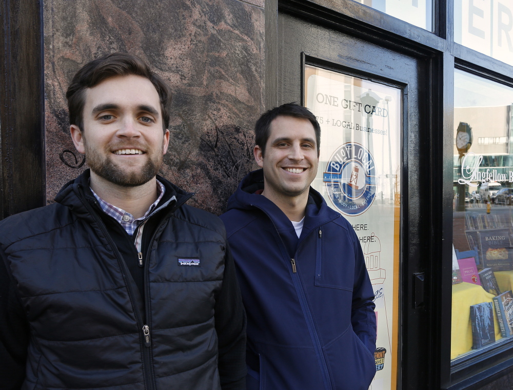 Sean Sullivan, left, and Kai Smith, co-founders of Buoy Local, stand outside Longfellow Books, which sells their gift cards.