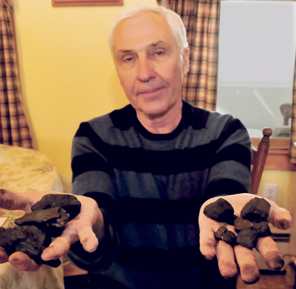 John Keister holds stove coal in his left hand and smaller nut coal at right that he uses for heat at his home in Norridgewock on Thursday.