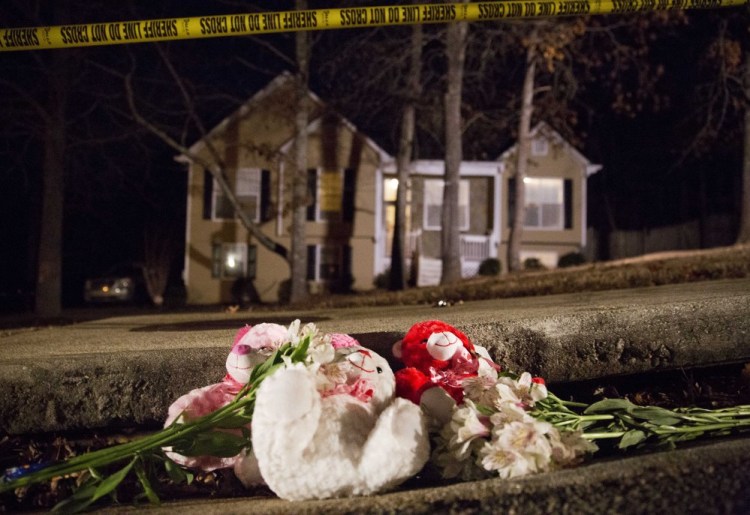 Flowers and teddy bears lay on the street outside the home of a shooting scene where authorities say five people are dead, including the gunman, in Douglasville, Ga. on Saturday.