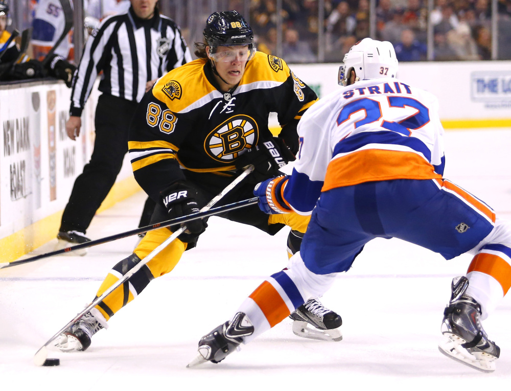 Boston’s David Pastrnak, left, moves to get around Islanders defenseman Brian Strait during the second period of the Bruins’ 2-1 victory at home on Saturday night. Boston has won nine of 12.