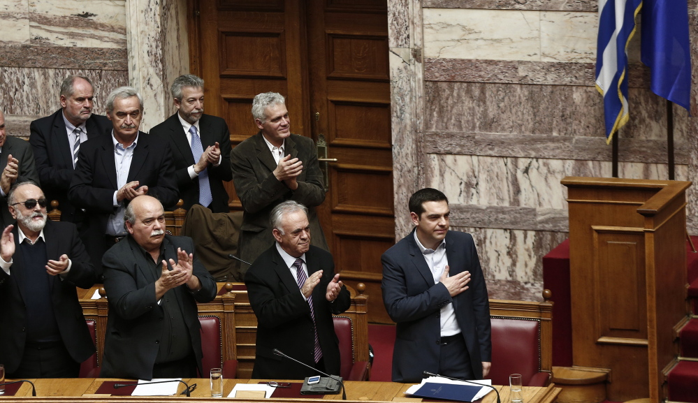 Greek Prime Minister Alexis Tsipras, right, acknowledges applause by members of his government Sunday following his first major speech in parliament in Athens
