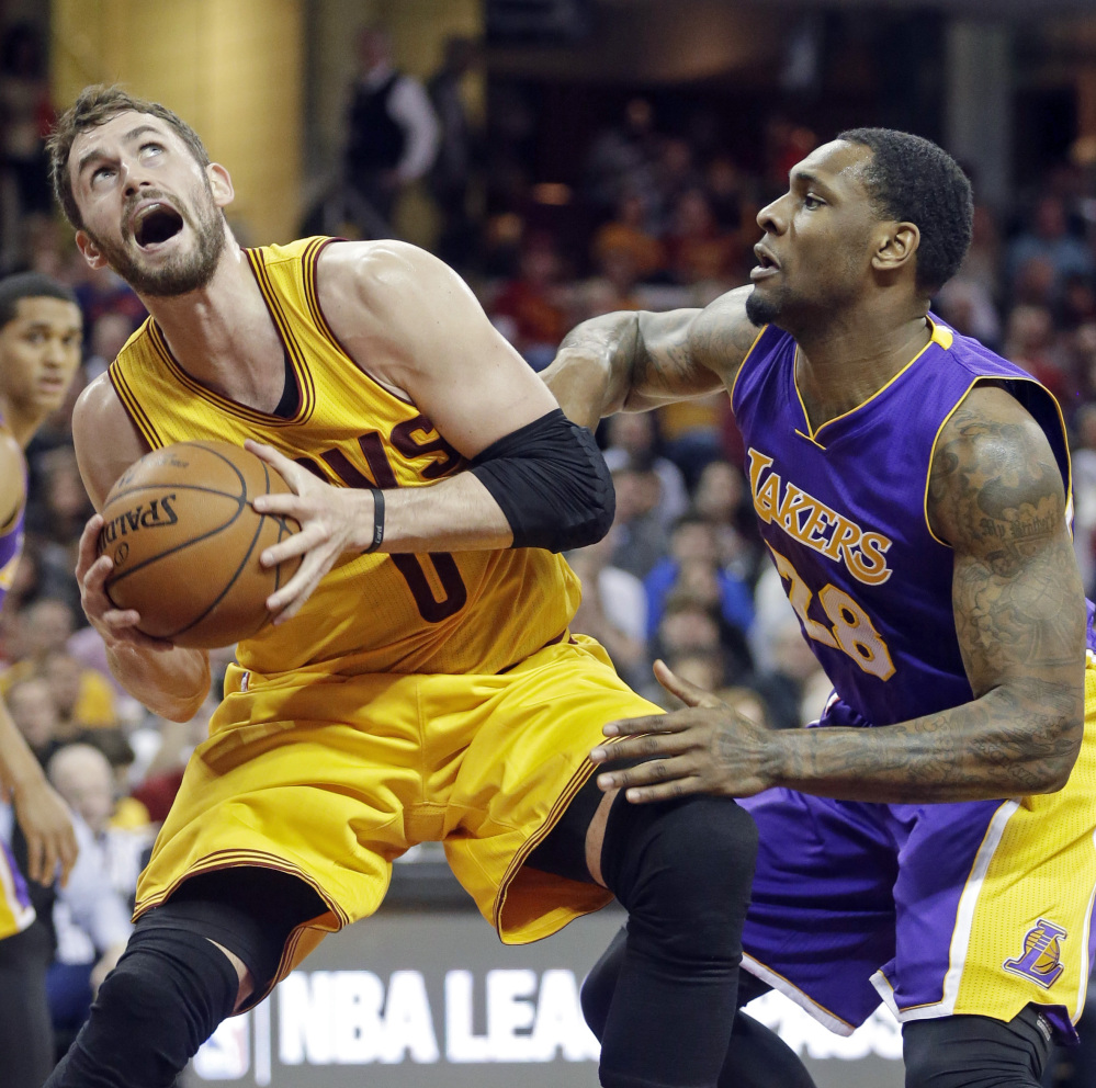 Cleveland’s Kevin Love, left, makes a move to the hoop while being defended by the Lakers’ Tarik Black on Sunday in Cleveland. Love scored 32 points and grabbed 10 rebounds to lift the Cavaliers to a 120-105 win.