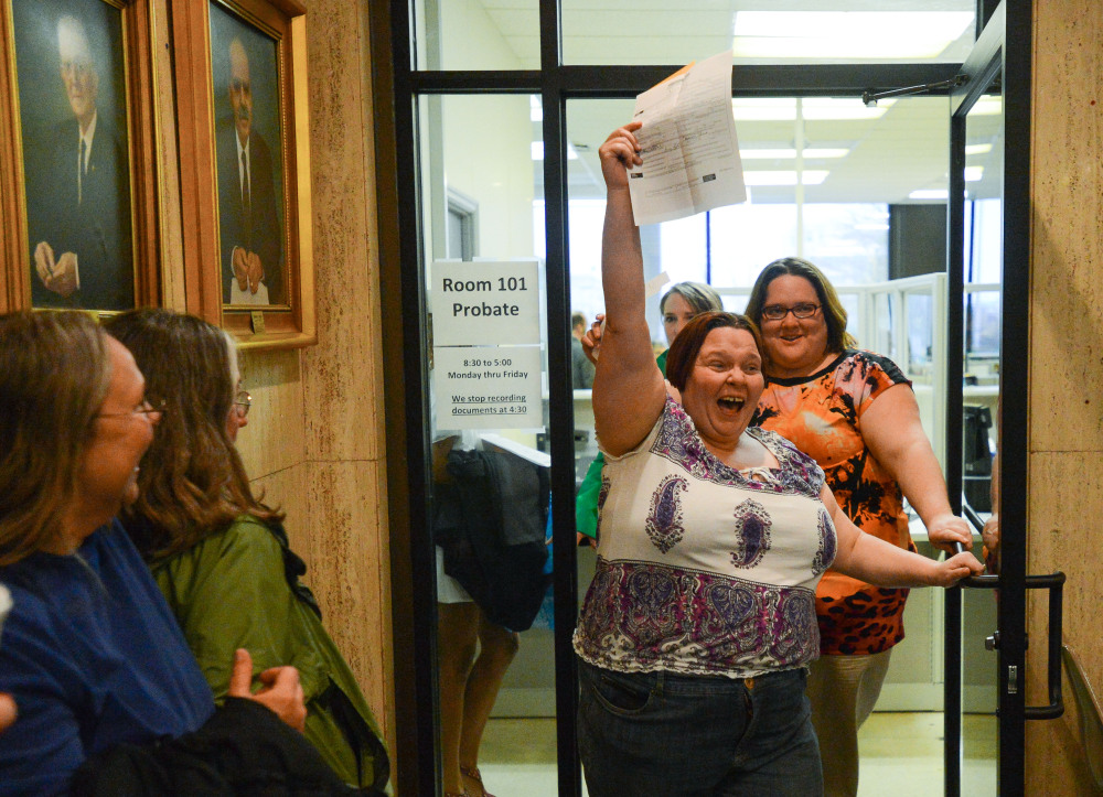 Eleanor Shue lifts her marriage license and yells in celebration as she and partner Jessica White emerge from the probate office after getting their marriage license in the Madison County Courthouse in Huntsville, Ala., on Monday.