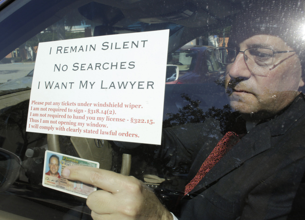 Florida attorney Warren Redlich displays a flier and his driver’s license for a reporter. Redlich says his goal is to protect the wrongly accused, not drunk drivers.