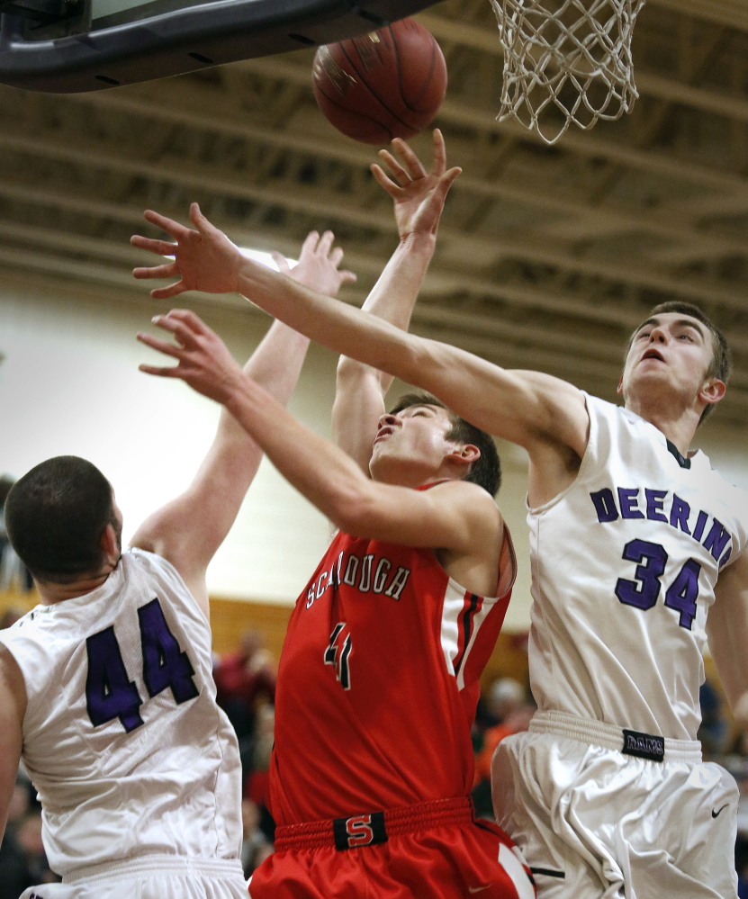 Raffaele Salamone, left, and Jacob Coon of Deering combine to block a shot by Reece Langerquist during the first quarter of their playoff game. 
Derek Davis/Staff Photographer
