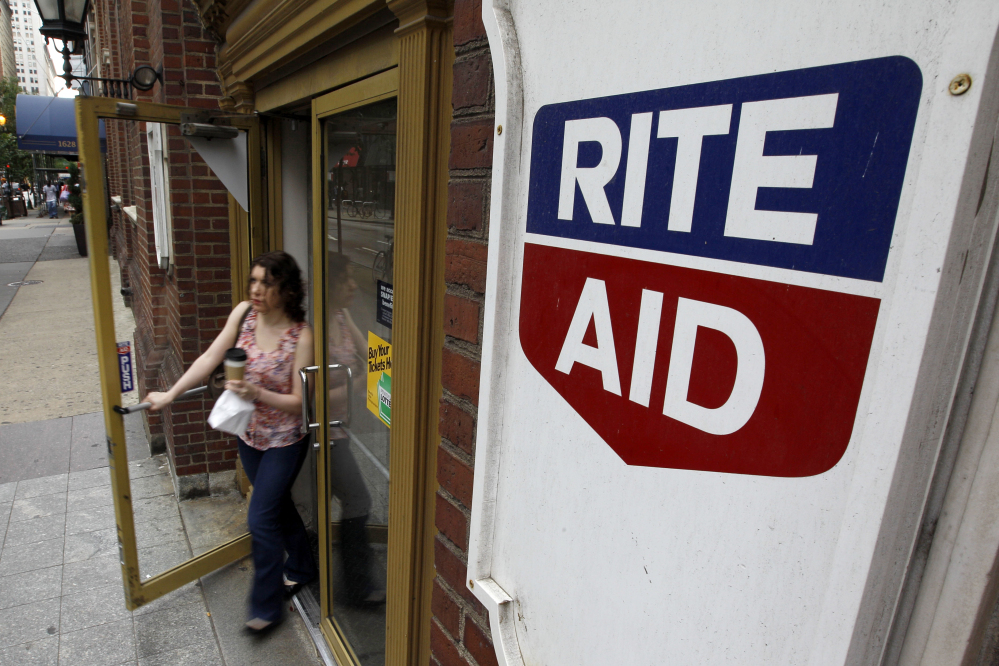 In this June 20, 2011, file photo, a woman exits a Rite Aid store, in Philadelphia. Rite Aid, announced Wednesday, Feb. 11, 2015, it is expanding from running drugstores into managing pharmacy benefits with a planned, $2 billion purchase of EnvisionRx.