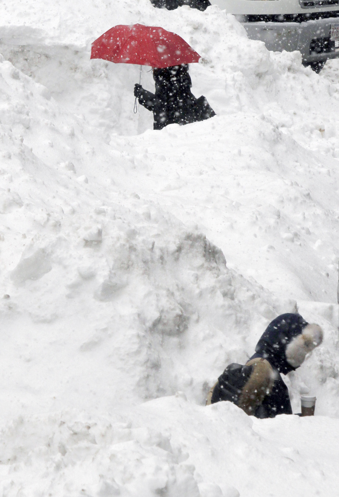 Commuters walk between piles of snow on a street in downtown Boston on Wednesday.