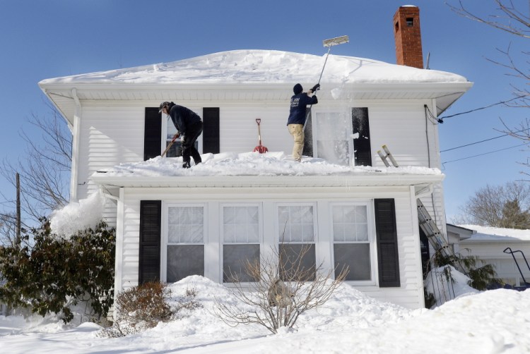Portland Property Services employees Larry Goodno, left, and Lewis Jarrett clear snow Wednesday off a house on Brighton Avenue in Portland. For homeowners who want to do the work themselves, if they don’t already have a roof rake they might not be able to find one in the sold-out stores.
