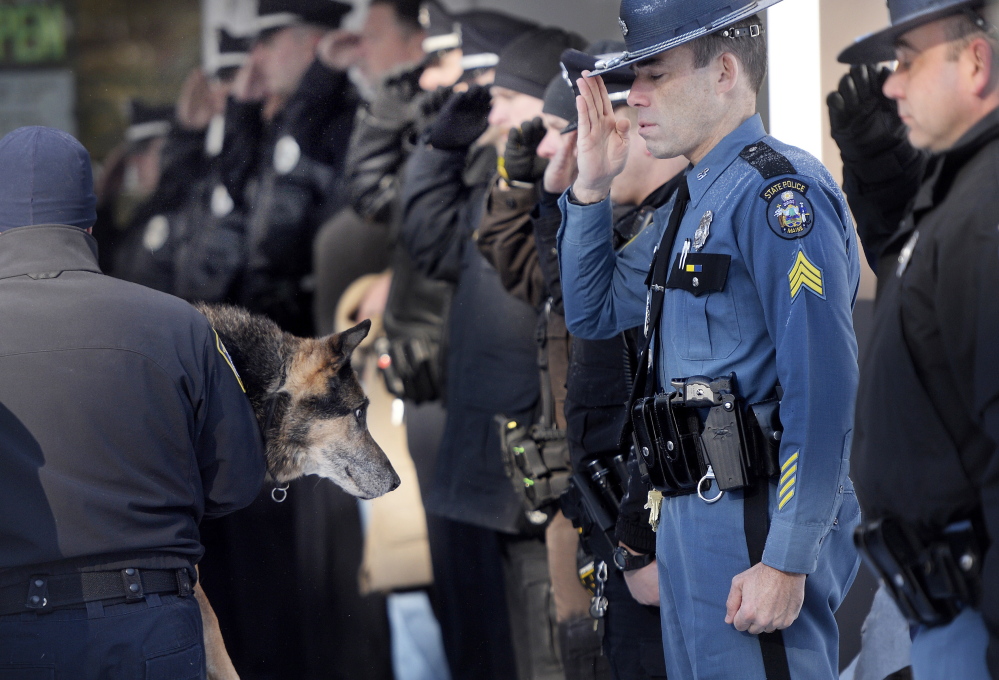 Sgt. Robert Burke of the Maine State Police salutes along with other officers as South Portland Police Officer Shane Stephenson carries Sultan, a retired Yarmouth police dog, into the Yarmouth Veterinary Center, where he was euthanized Friday.