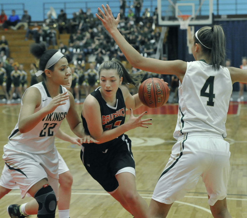 Adrianna White of Brunswick drives between Oxford Hills’ Tiana Sugars, left, and Anna Winslow during an Eastern Class A quarterfinal Friday at the Augusta Civic Center. Brunswick advanced with a 37-32 win.