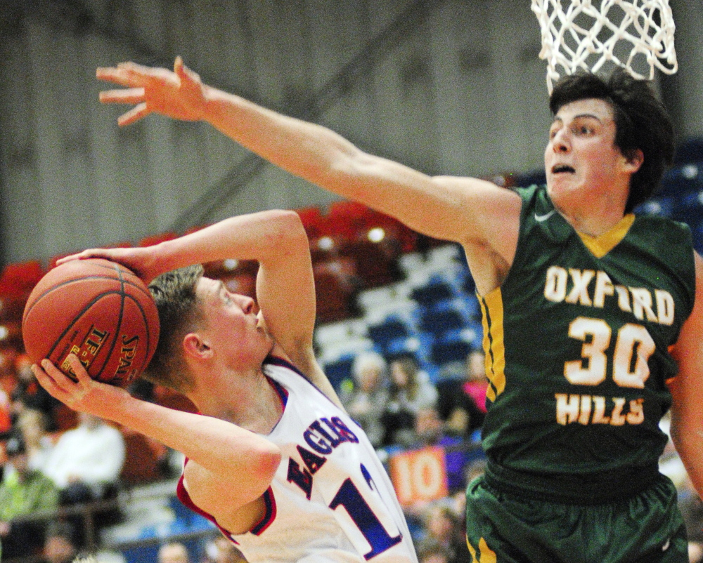 Messalonskee guard Trevor Gettig, left, takes a shot while Oxford Hills forward Patrick Marco plays defense during the Eagles’ 58-42 win in the Eastern A quarterfinals.