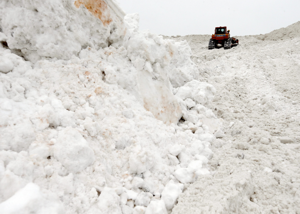 A bulldozer works on a giant pile of snow at a “snow farm” in Boston on Saturday. Crews from around the region worked urgently to remove snow Saturday as another storm bore down on the Northeast.