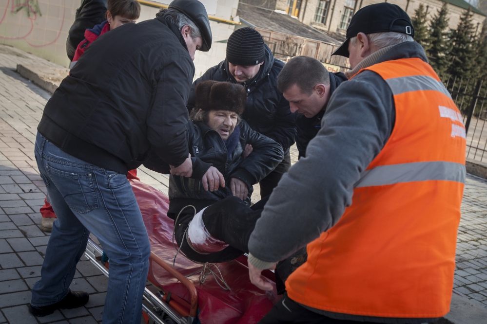 People and paramedics place a wounded man onto a stretcher after shelling between pro-Russian rebels and the Ukrainian government forces in Donetsk, Ukraine, Saturday.