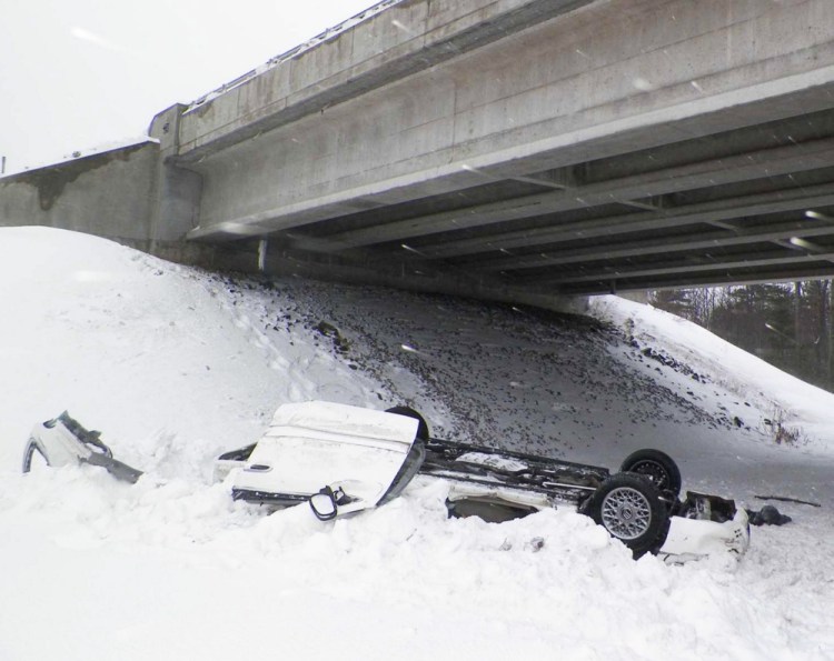 Car rests on its roof after the driver lost control and went over the top of a snowbank and off the bridge.