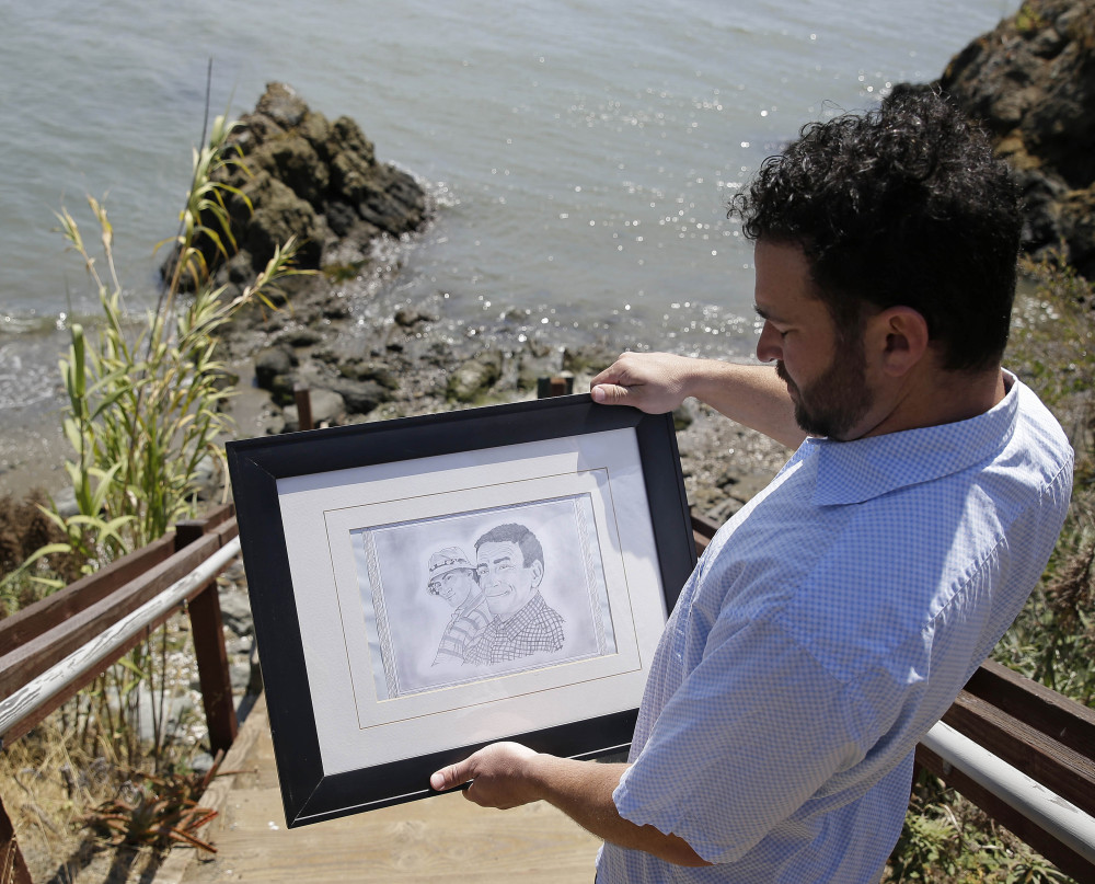 Dan Ager looks at a graphite sketch showing him and his father, Alan Ager, while walking toward a beach outside San Quentin State Prison in San Quentin, Calif. Alan Ager was killed in 2010 at Salinas Valley State Prison.