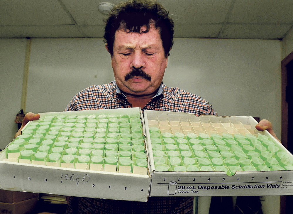 Northeast Lab Services owner Rodney Mears holds two trays of water samples to be tested for radon at the Winslow facility in this 2014 file photo. The company saw a spike in business following a new state law that requires landlords to test for radon.