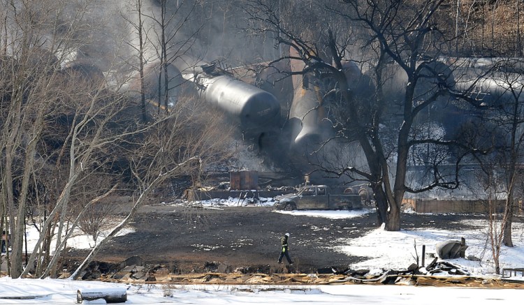 A crew member walks near the scene of the train derailment near Mount Carbon, W.Va., on Tuesday. A CSX train carrying more than 100 tankers of crude oil derailed in a snowstorm, sending a fireball into the sky and threatening the water supply of nearby residents.