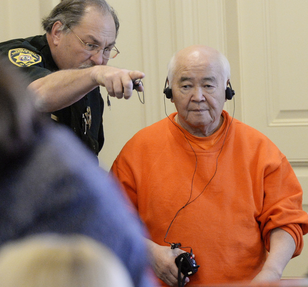 James Pak is directed to his seat in York County Superior Court in Alfred on Thursday. Pak has entered a plea of not guilty by reason of insanity on two counts of murder in the deaths of Derrick Thompson, 19, and Alivia Welch, 18. Pak has difficulty hearing and uses headphones hooked up to a transmitter that receives audio from the microphone system. 