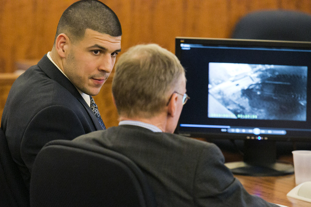 Former NFL player Aaron Hernandez looks at his attorney as security footage is seen on a monitor during his murder trial at the Bristol County Superior Court on Friday.
