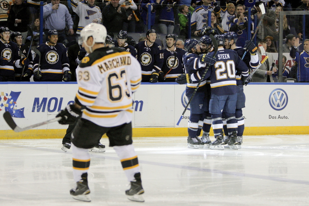 The Bruins’ Brad Marchand skates off the ice as St. Louis Blues teammates congratulate Petteri Lindbohm after his goal in the second period of the Blues’ win Friday night in St. Louis.