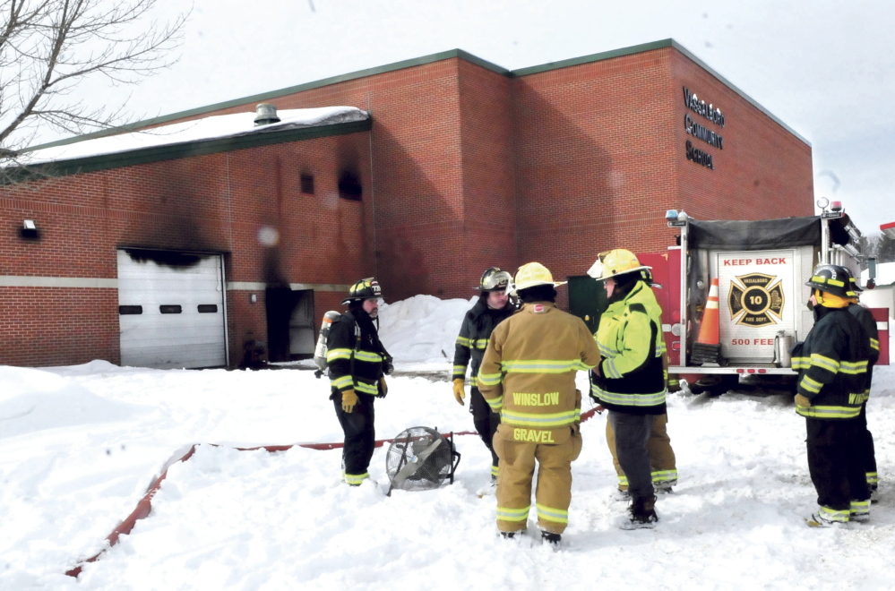 Firefighters from Vassalboro and Winslow wait as the Vassalboro Community School is ventilated of black smoke after a tractor caught on fire inside the attached garage, causing substantial damage on Sunday.