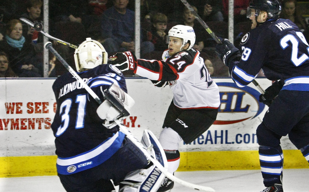 Pirates center Brendan Shinnimin, center, tries to control a wild puck in front of IceCaps goalie Jussi Olkinuora with defensive pressure from Jordan Hill on Sunday.