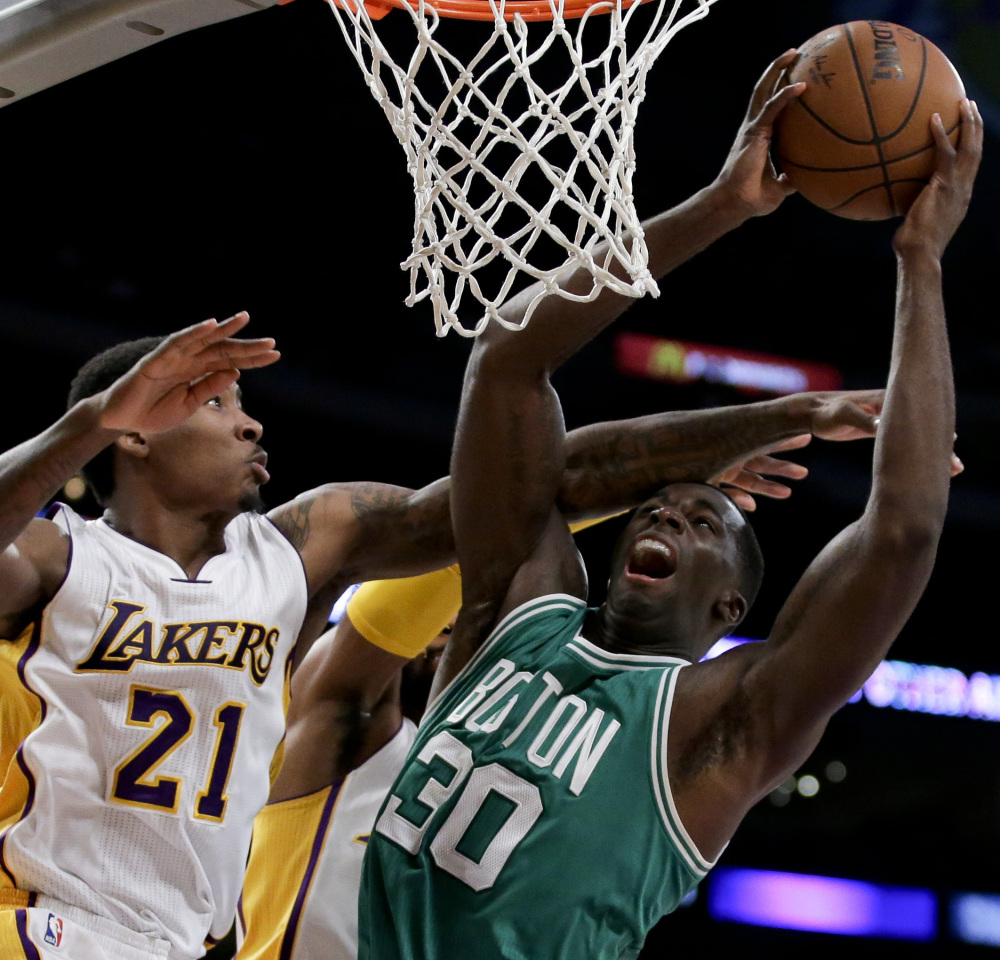 Celtics center Brandon Bass, right, takes a shot while being defended by Lakers forward Ed Davis during the first half of their game Sunday in Los Angeles. The Lakers won, 118-111 in overtime.