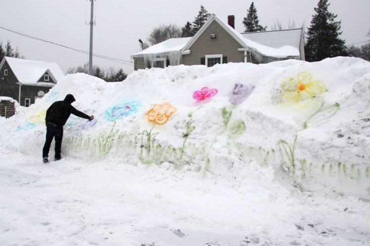 William Green, 25, spray paints flowers on a snowbank in the parking lot of Genrich’s Garden Center where he works in Irondequoit, New York. This has been one of the coldest Februarys on record in the region with frigid temperatures and more snowfall forecast for the coming week.