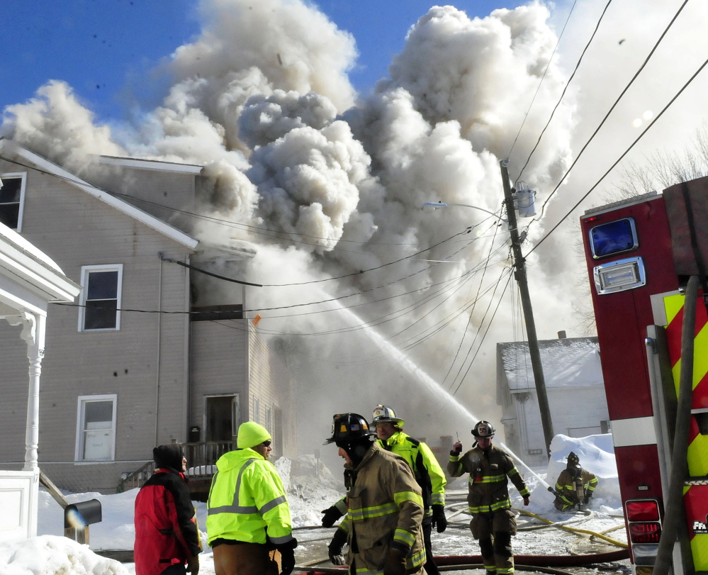 Wind-blown smoke billows from an apartment building on Paris Street in Waterville that was destroyed by fire Monday.