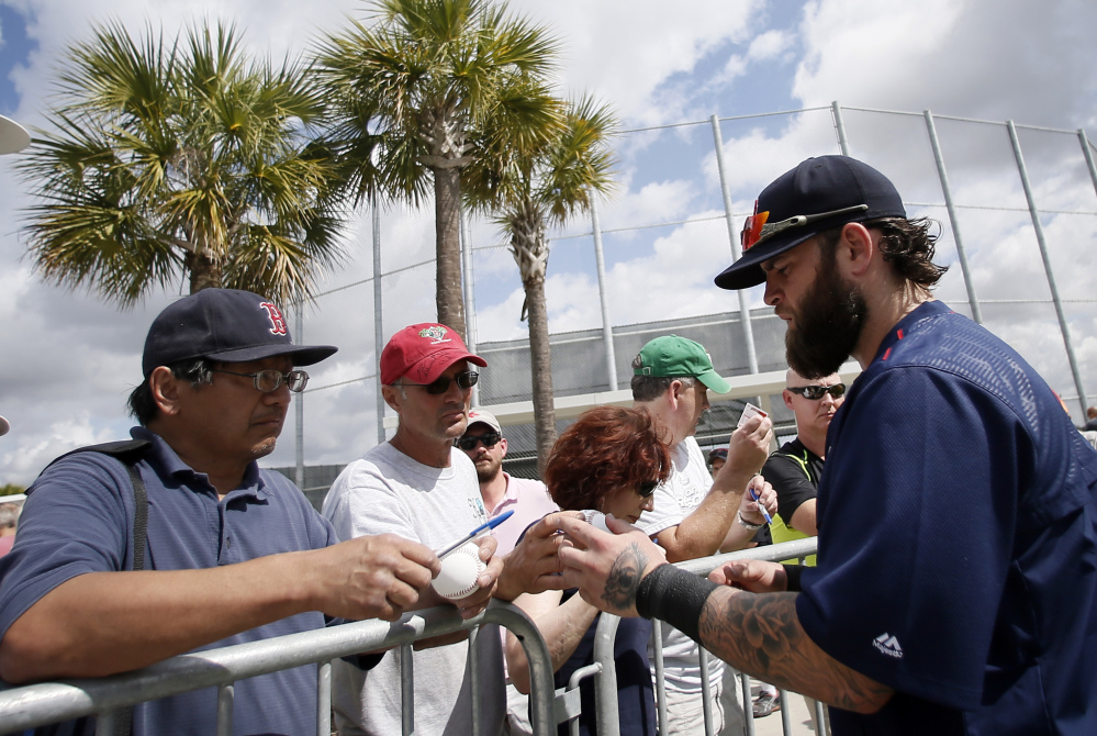 Boston Red Sox's Mike Napoli, right, signs autographs for fans after a workout Monday at spring training in Fort Myers Fla. 
The Associated Press 