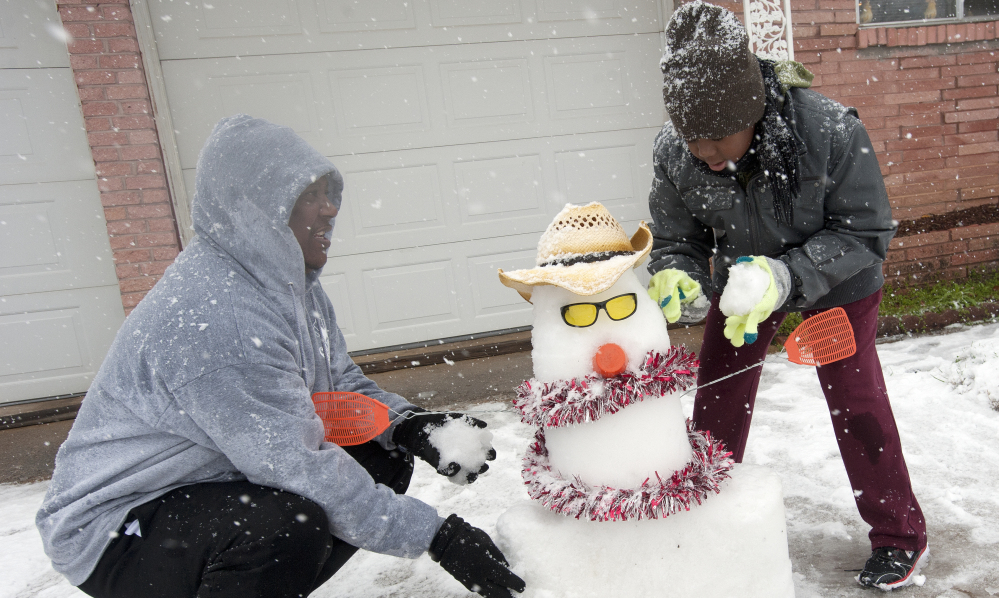 Kenneth Scott, left, and his son Kanya build a snowman Wednesday in Tyler, Texas. Six to 8 inches of snow or more fell from north Texas to Virginia.