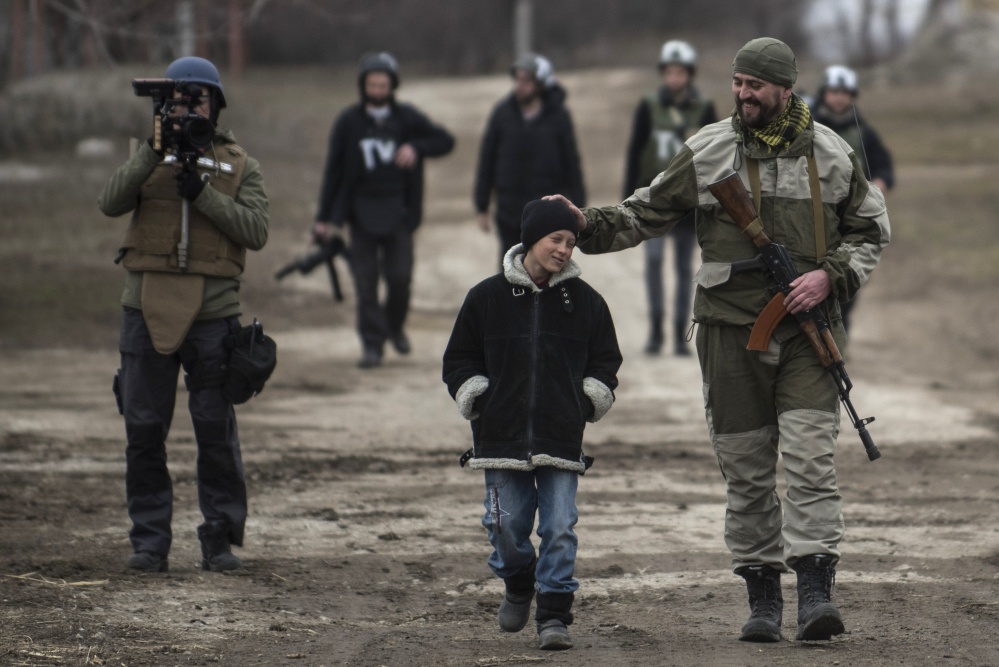 A Ukrainian serviceman speaks with a schoolboy in the village of Chermalyk, eastern Ukraine, on Thursday. In a long-awaited development, Ukrainian forces and separatist fighters both announced Thursday they are moving heavy weapons from the front line in eastern Ukraine. The Associated Press