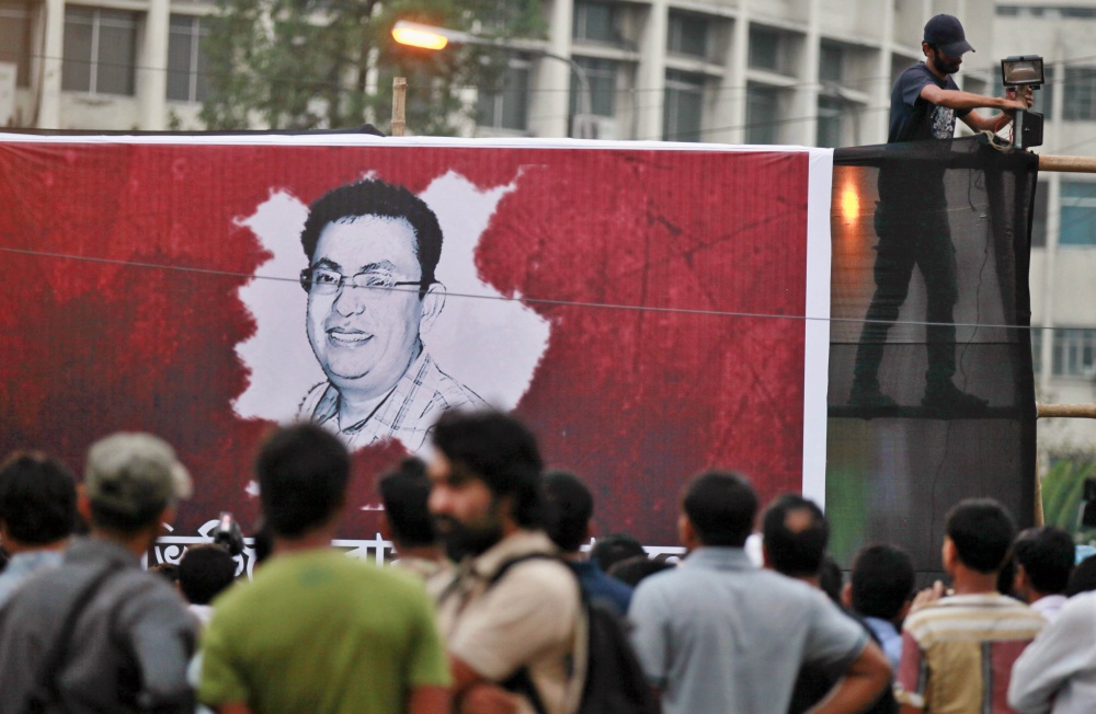 A Bangladeshi activist sets up a light on a poster displaying a portrait of Avijit Roy as others gather during a protest against the Roy in Dhaka, Bangladesh, on Friday. 