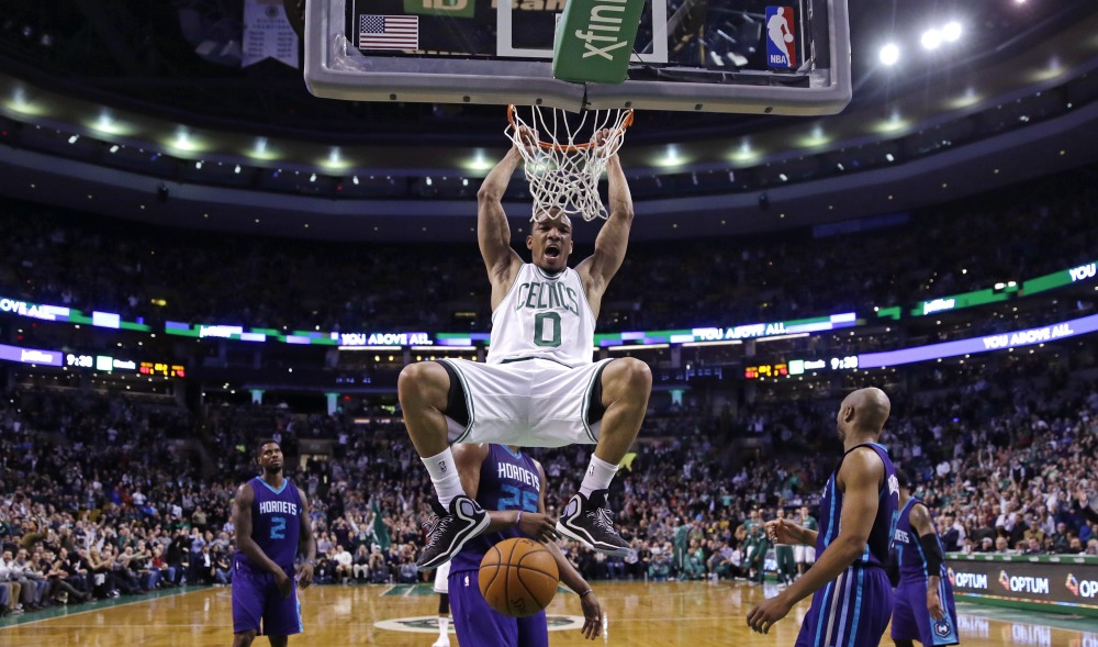 Celtics guard Avery Bradley hangs from the rim after slamming a dunk against the Charlotte Hornets in the second half of Friday night’s game in Boston. The Celtics defeated the Hornets, 106-98, after trailing by 16 points in the third quarter.
