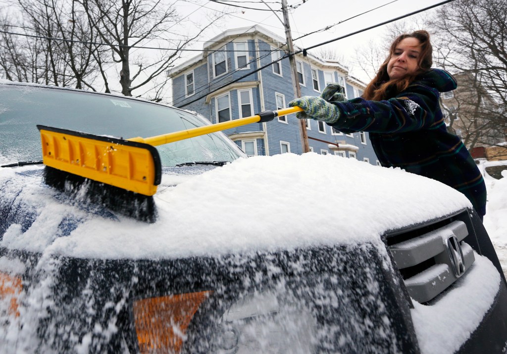 Karen Landis of Portland brushes a fresh layer of snow from her vehicle Sunday. Derek Davis/Staff Photographer