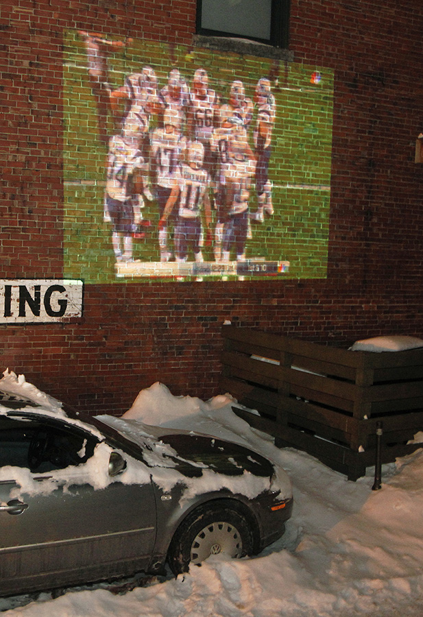 The Super Bowl is projected onto a brick wall for viewing at The Thirsty Pig where seating was built out of snow Sunday. Jill Brady/Staff Photographer