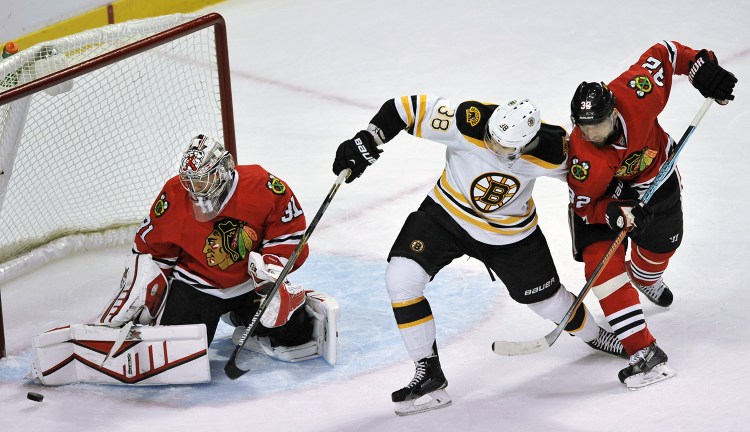 Chicago Blackhawks goalie Antti Raanta (31) makes a save against Boston Bruins' Jordan Caron (38) while Blackhawks' Michal Rozsival (32), of The Czech Republic, looks on during the second period of an NHL hockey game Sunday. The Associated Press