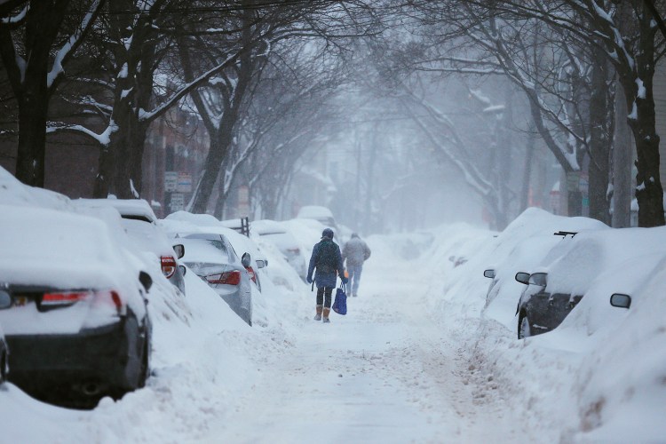Pedestrians make their way along a snow-covered street during a Feb. 9 , 2015 winter storm in Cambridge, Mass.
