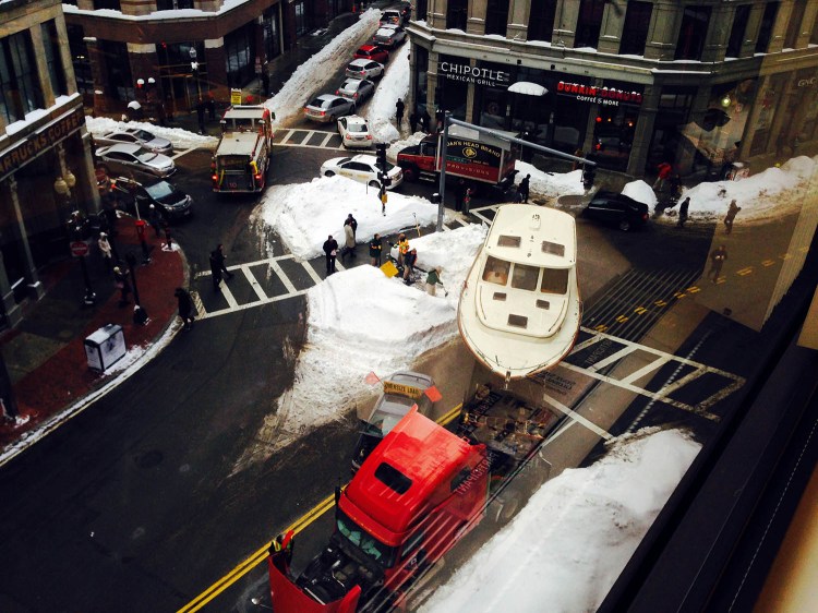 In this photo taken through a window, a large truck towing an even bigger boat broke down in downtown Boston, snarling traffic in the heart of the city's Financial District on Wednesday.