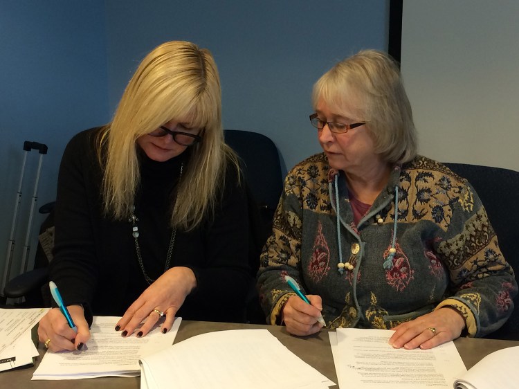 Maine Virtual Academy board Chairwoman Amy Carlisle, left, signs the contract opening the state's second virtual charter school as Maine Charter School Commission Chairwoman Shelley Reed looks on.
