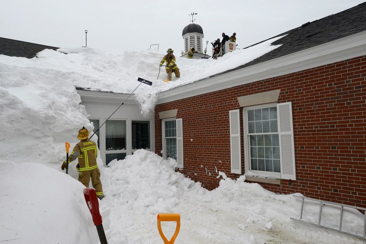 Firefighters from Ogunquit and Wells shovel snow off the Wells Public Library roof Thursday that is partially bowed under the weight.