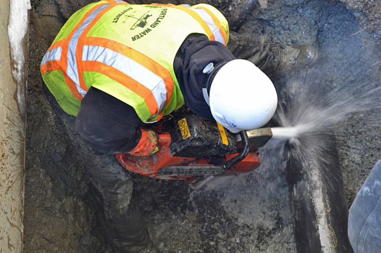 Evan Haines of the Portland Water District cuts a pipe Monday while repairing a water main that ruptured under Stroudwater Street in Westbrook. A section of cast iron pipe was replaced.