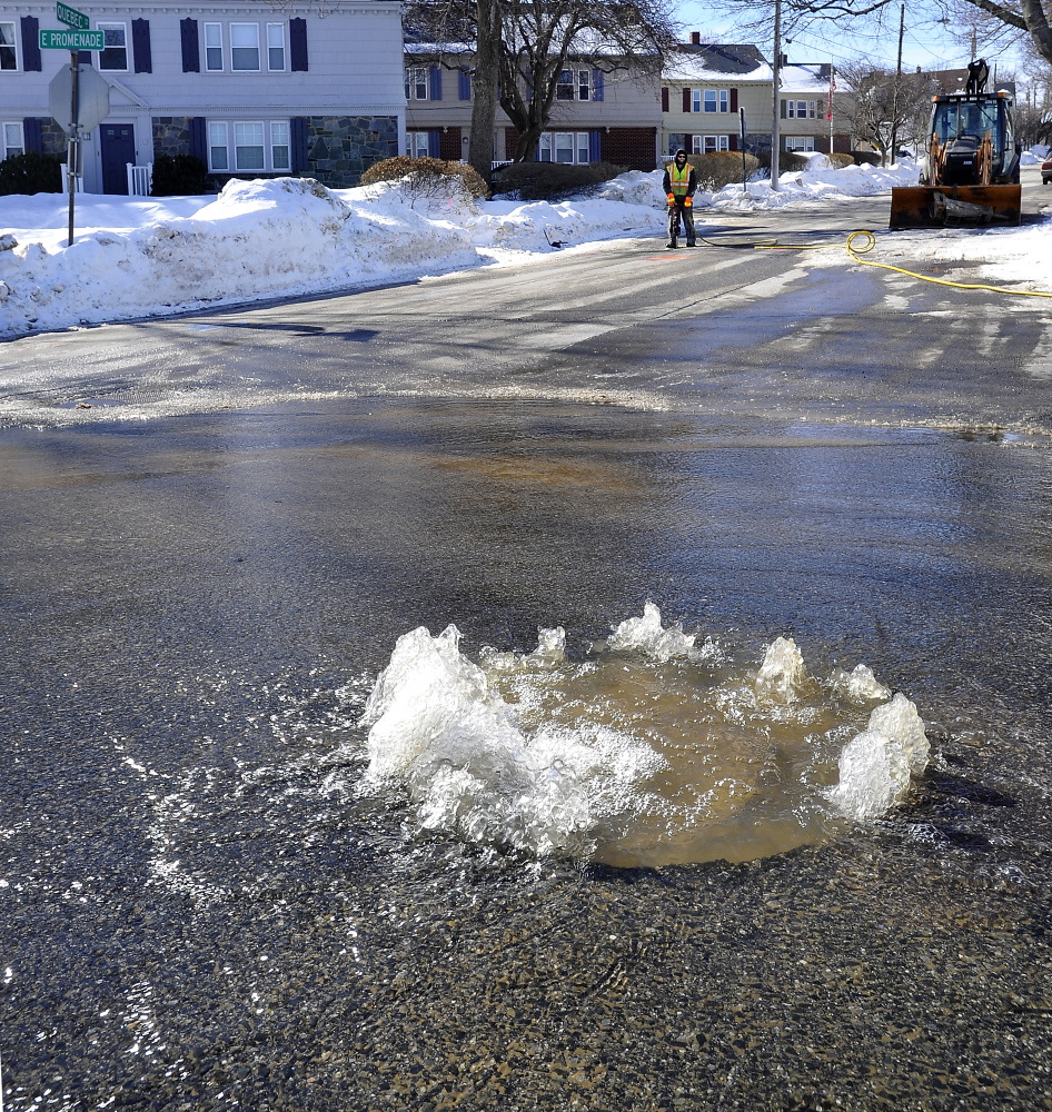 Water bubbles up from a broken main while a Portland Water District worker waits for a portable air compressor to start delivering air to his jackhammer as work begins on a water main break at the corner of Quebec Street and Eastern Promenade in Portland.